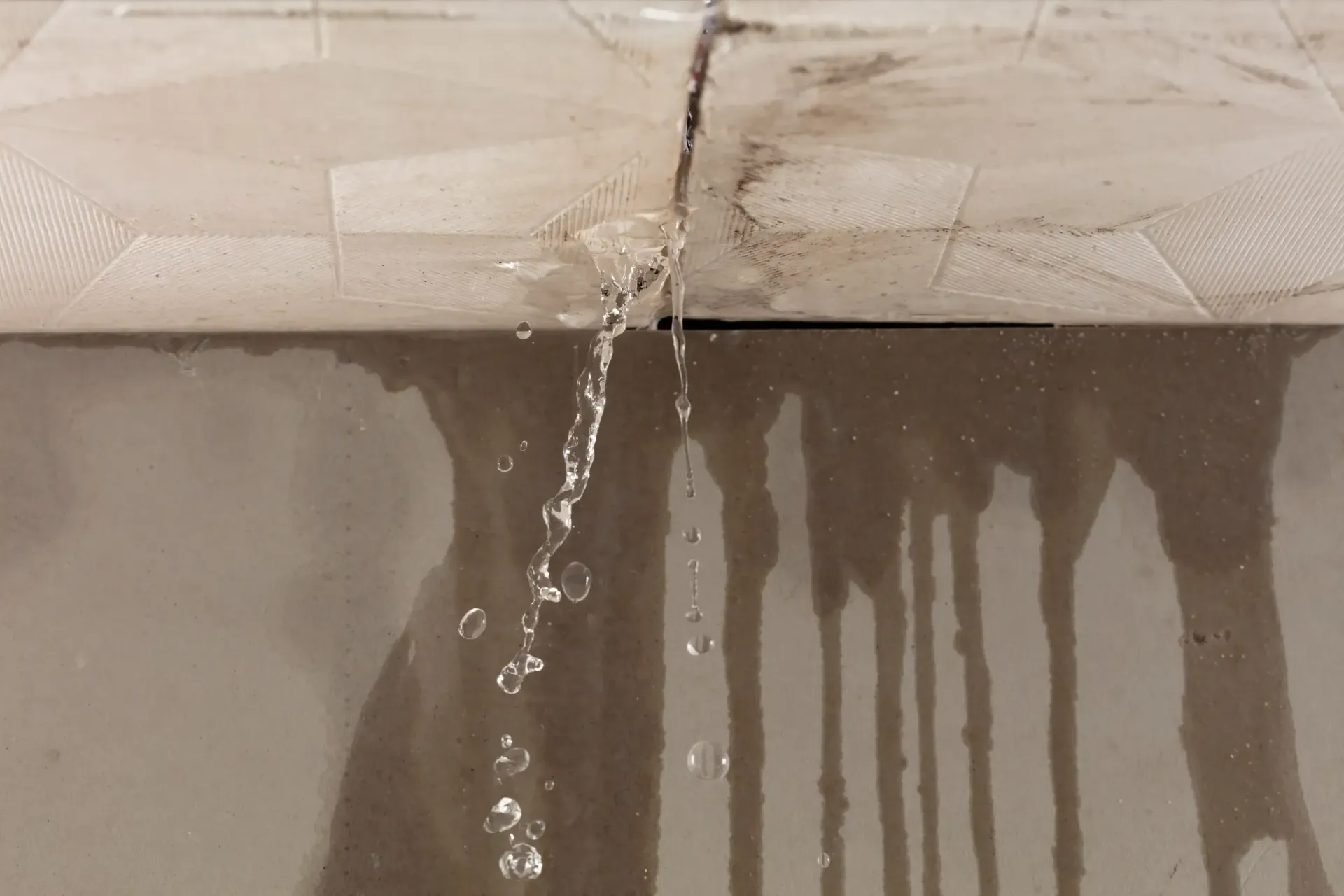 Roof leaks causing water dripping from ceiling with visible water damage stains