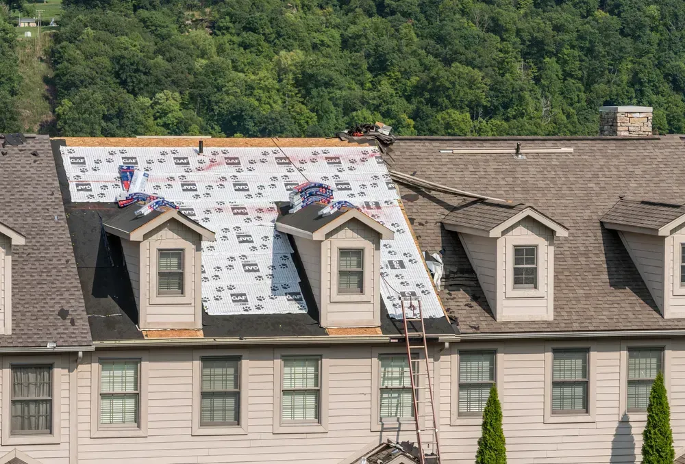 Roofing contractor has laid waterproof liner on townhouse roof before adding the new shingles