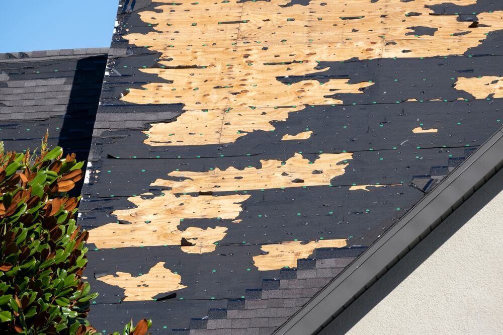 Wind-damaged roof with missing asphalt shingles