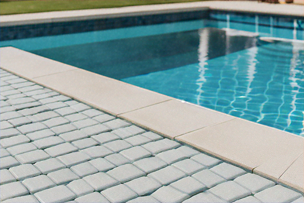Poolside view with paved patio and turquoise water.
