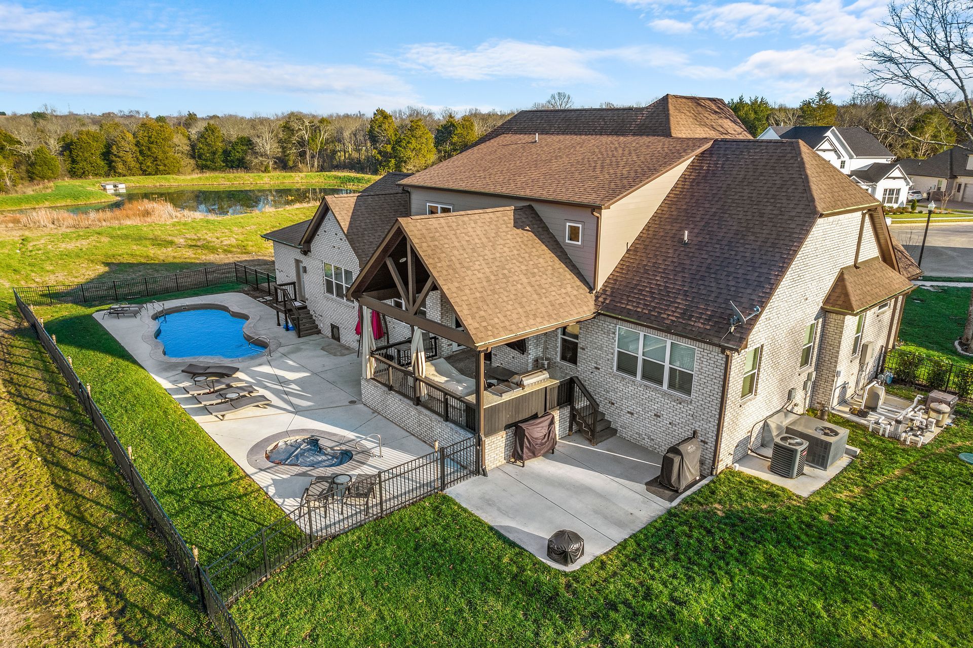Two-story house with a screened porch and a pool in the backyard. Blue sky.