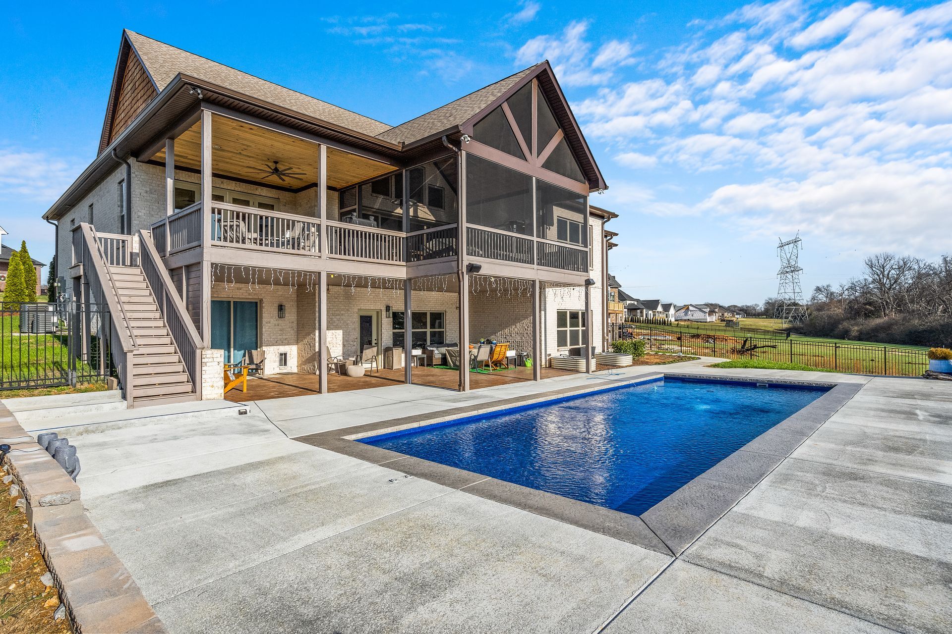 Two-story house with a screened porch and a pool in the backyard. Blue sky.