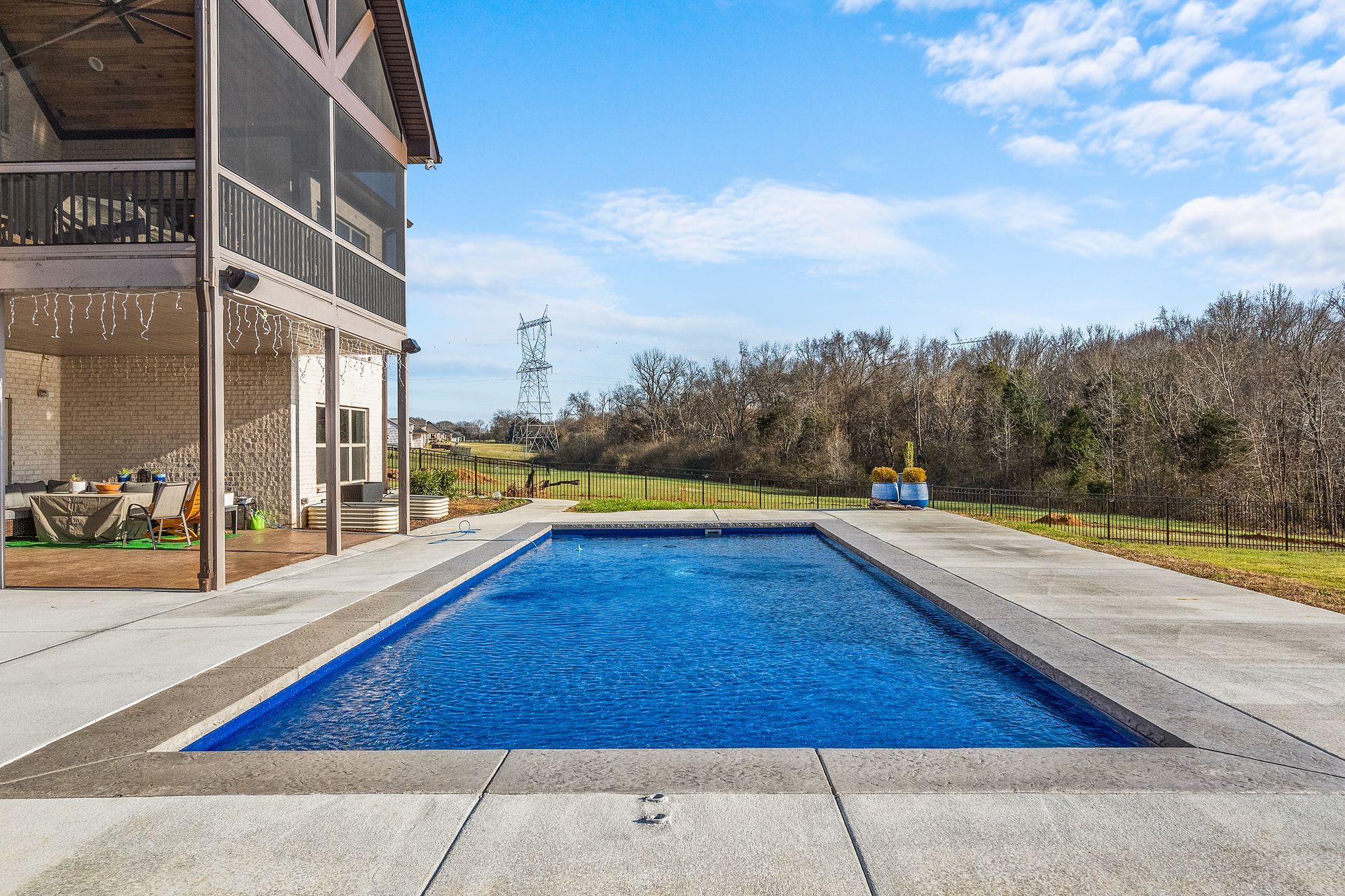 A rectangular pool filled with blue water next to a two-story building with a balcony; sunny day.