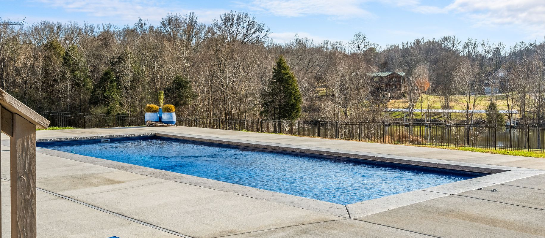 Hot tub on a patio next to a house with a covered porch.