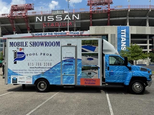 Rectangular pool with turquoise water, surrounded by wooden decking and three striped lounge chairs.