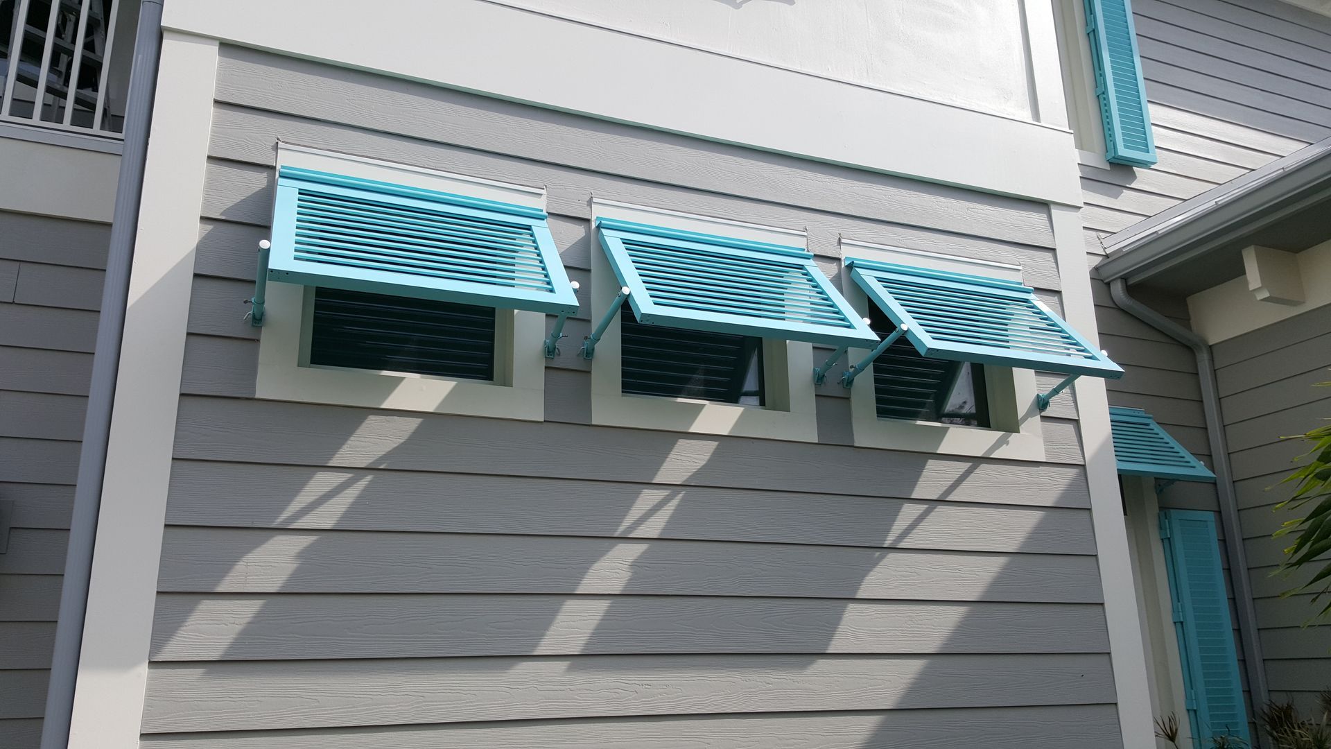 A gray house with blue awnings on the windows