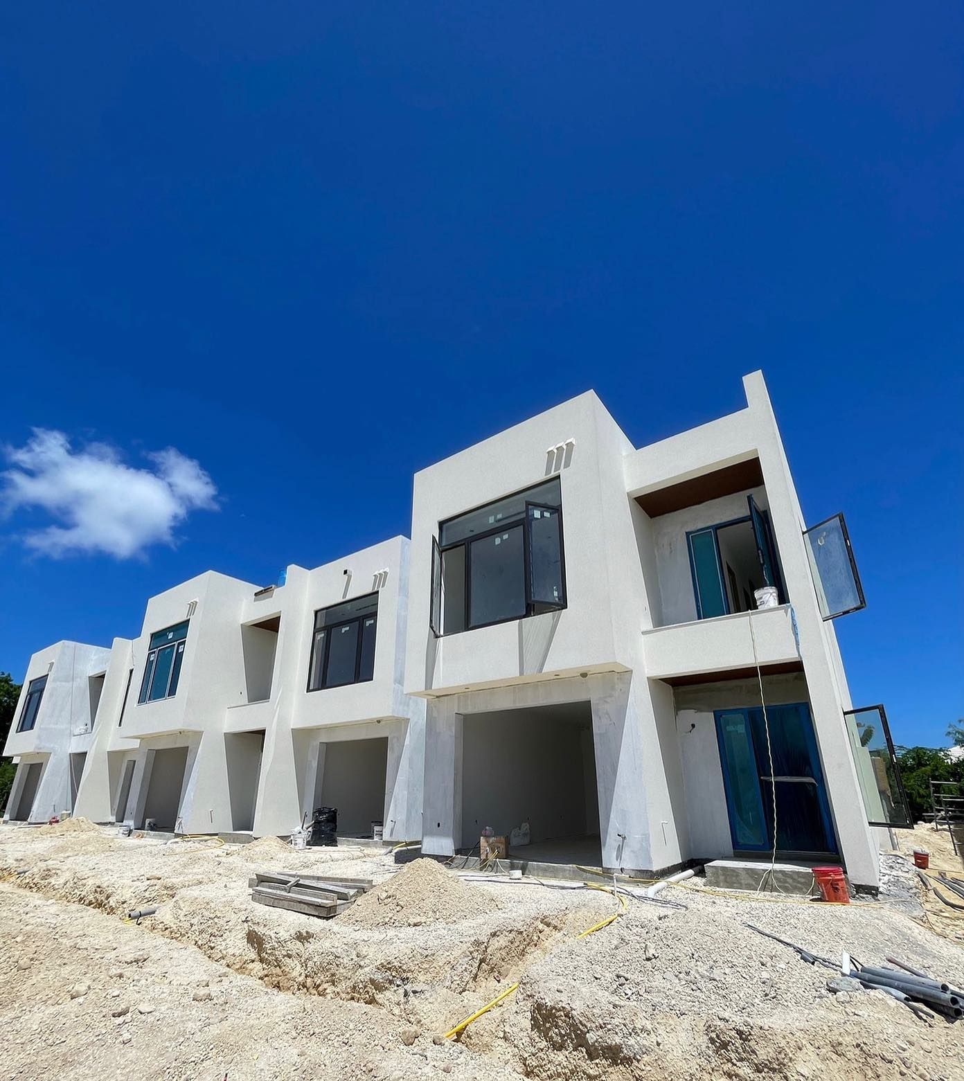 A large white building with a blue sky in the background is under construction.