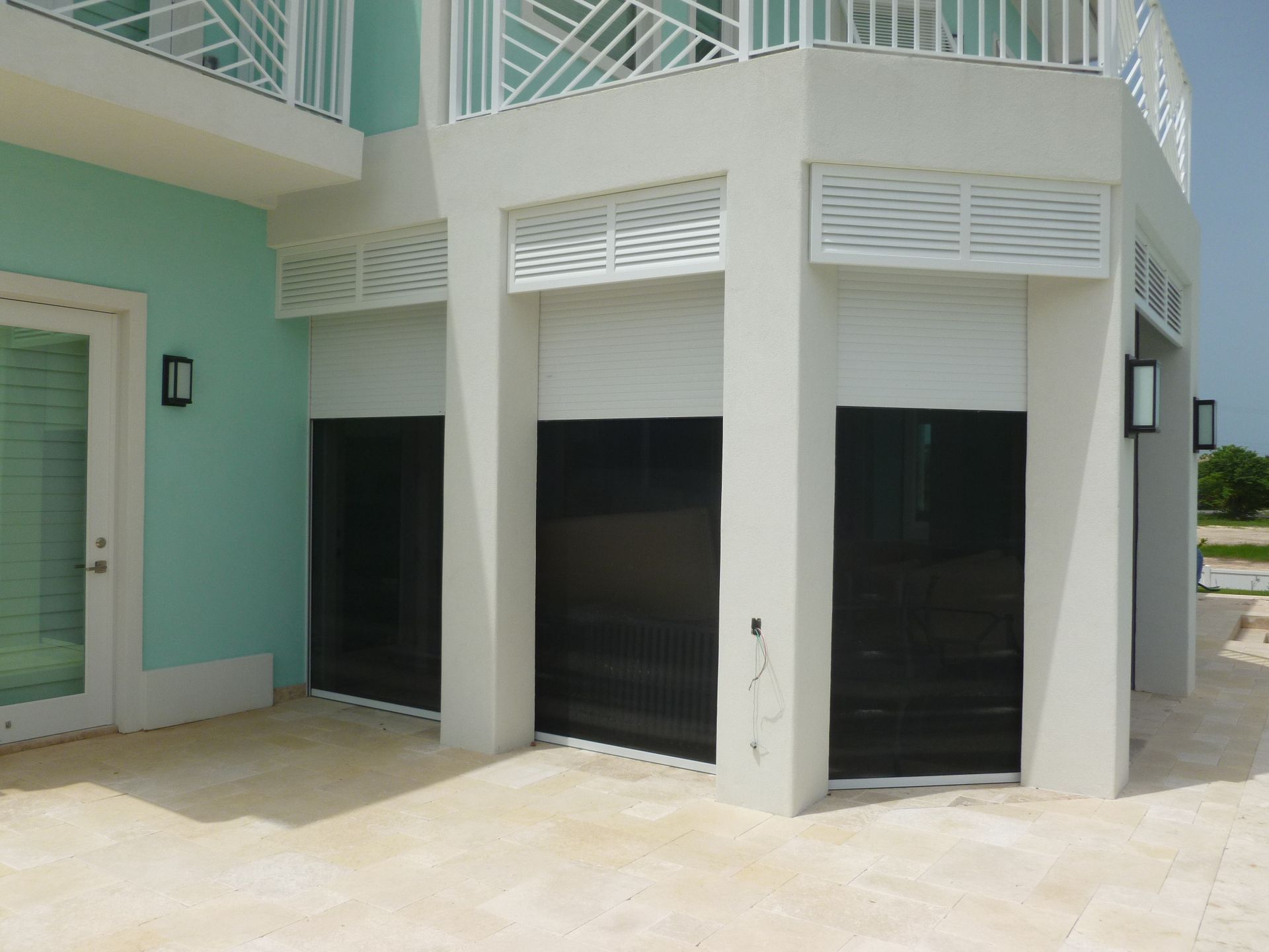 A white house with a balcony and black doors