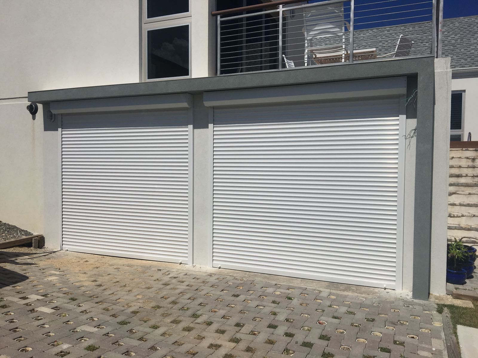 A white garage door is sitting next to a white house.
