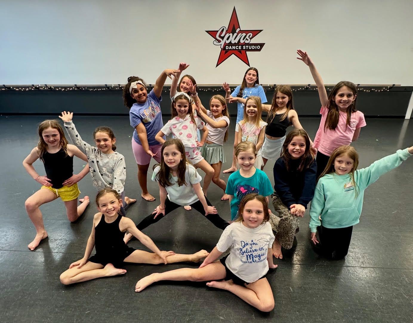 A group of young girls are posing for a picture in a dance studio.