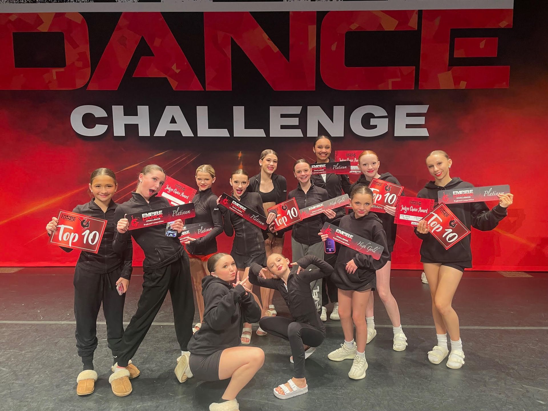A group of young girls are posing for a picture on a dance stage.