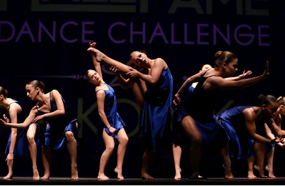 A group of women are dancing in front of a dance challenge sign