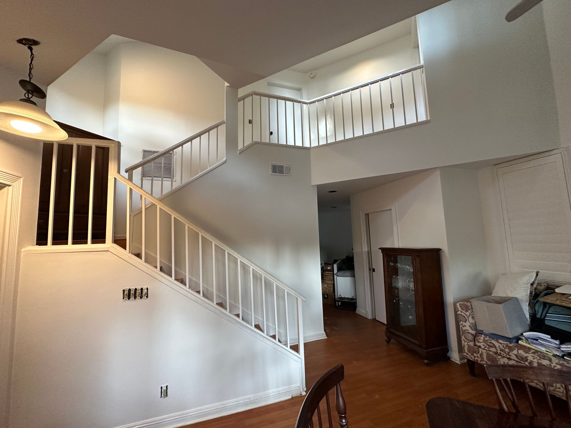 White staircase with railing leads to upper level; entry hallway and furniture are visible.