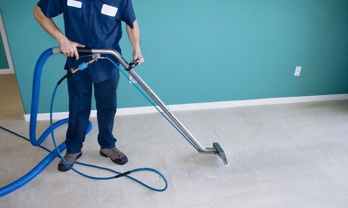 A man is cleaning a carpet with a vacuum cleaner
