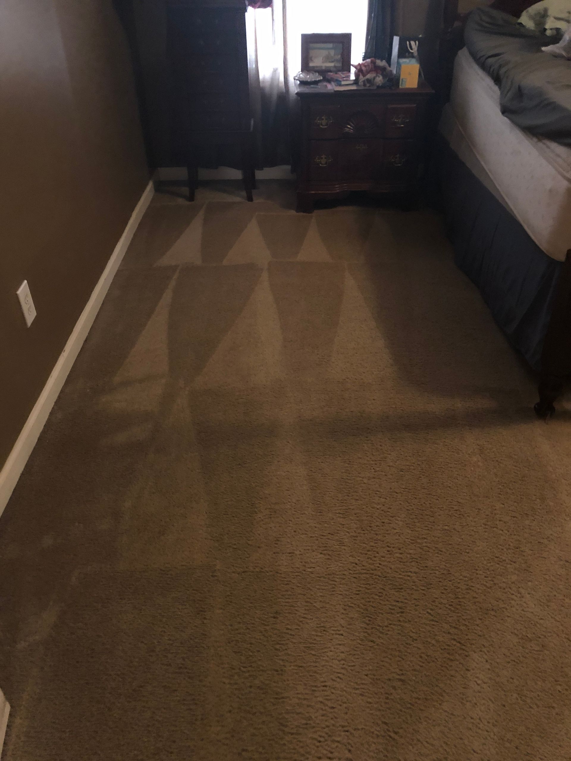 A bedroom with a bed , nightstand , and carpet.