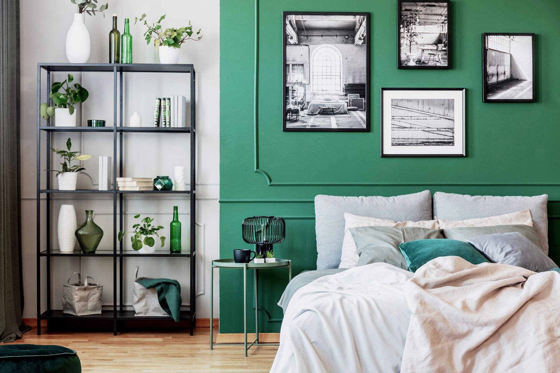 A bedroom with green walls, a bed, a bookshelf, and pictures on the wall.