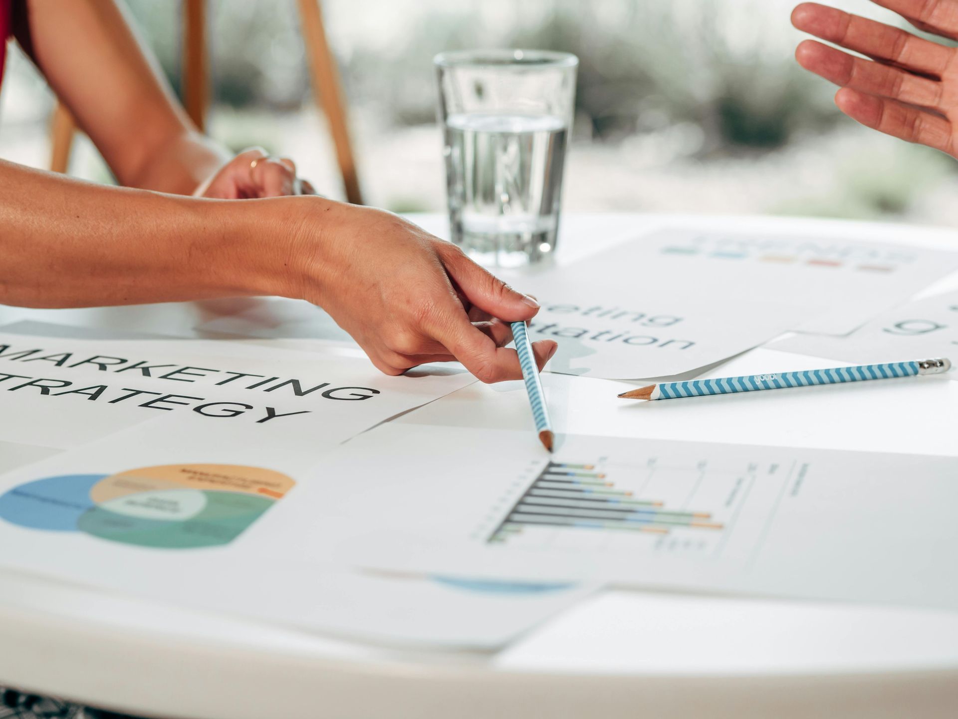 Hands pointing at charts and notes during a meeting table discussion