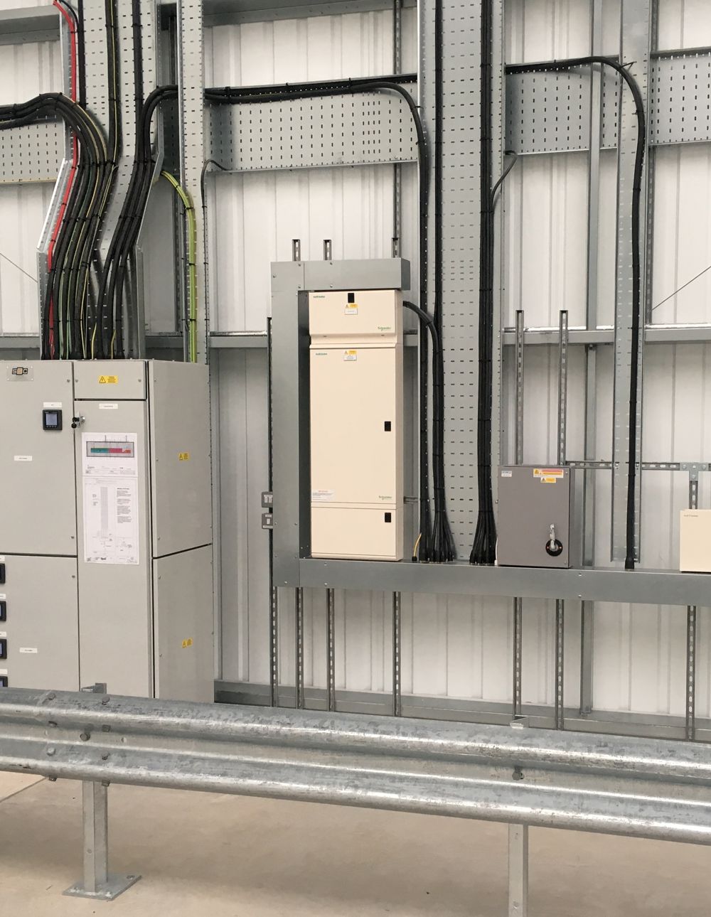 Electrical panel with cables, metal structure. Light gray and black colors. Industrial interior.