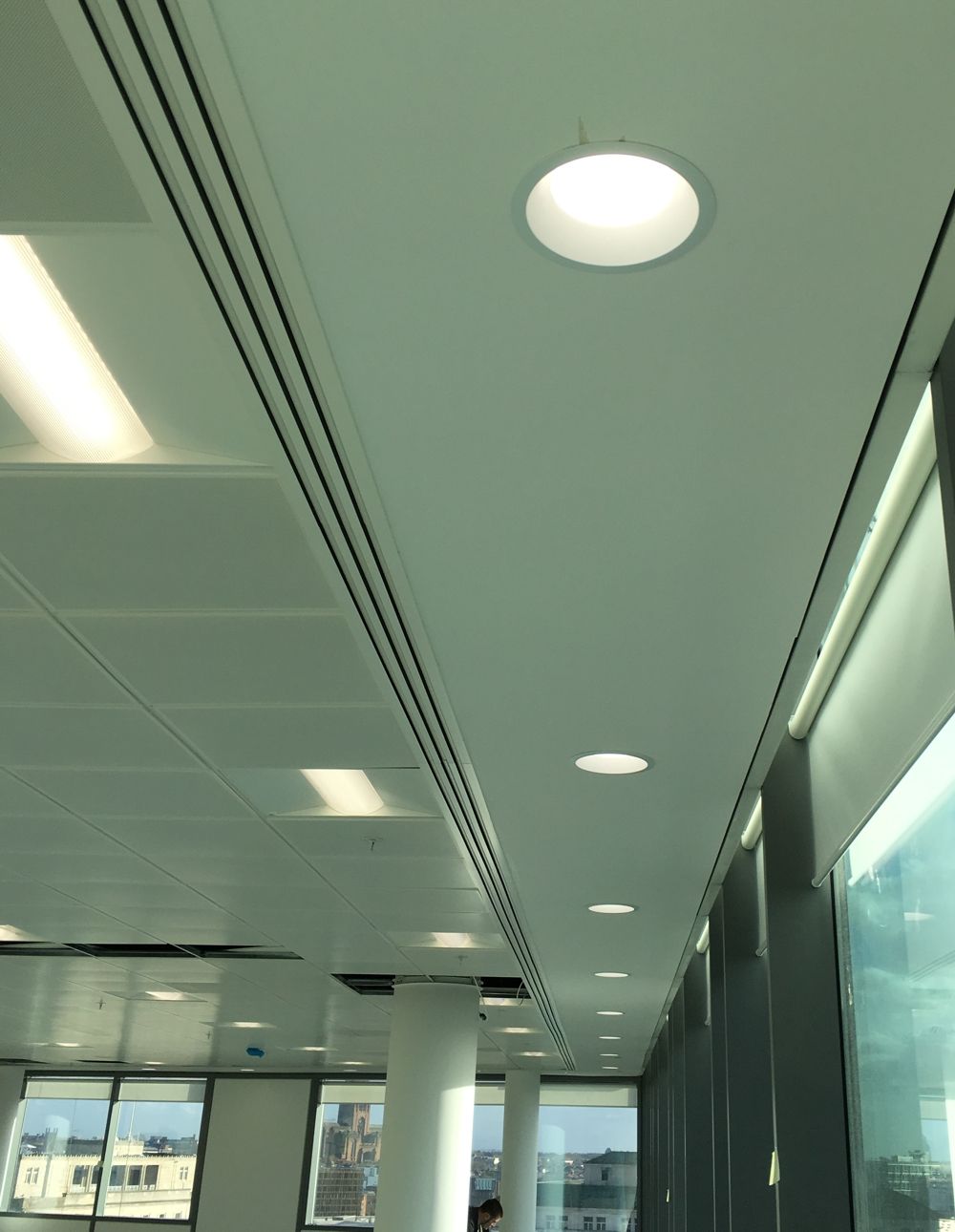 Office ceiling with recessed lights and air vents; daytime interior.