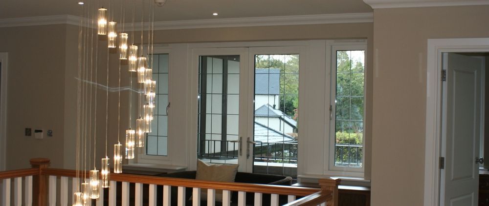 A well-lit interior with a spiral chandelier, windows, and a wooden railing.
