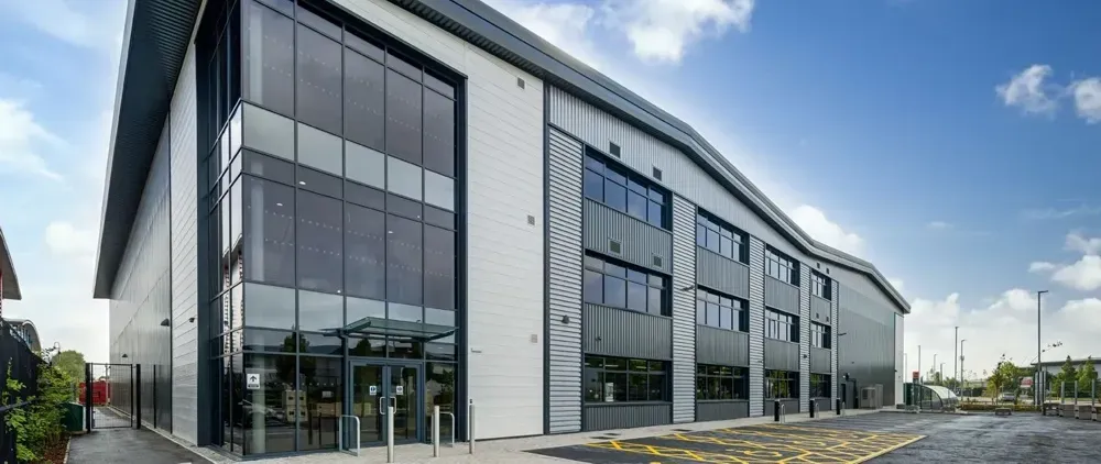 Modern commercial building with large windows, gray and white facade, and a blue sky.