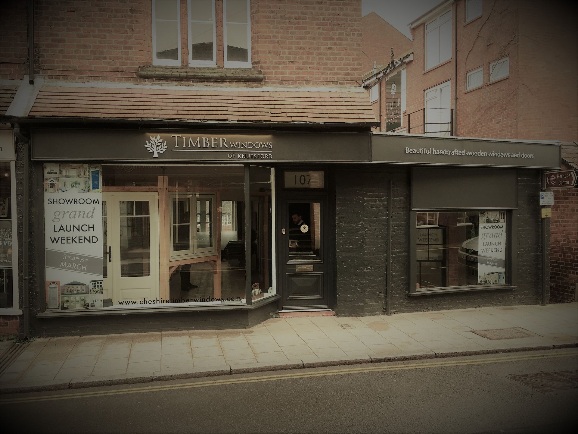 Timber & Oak storefront, displaying doors. Grand opening sign. Dark gray and brick exterior.