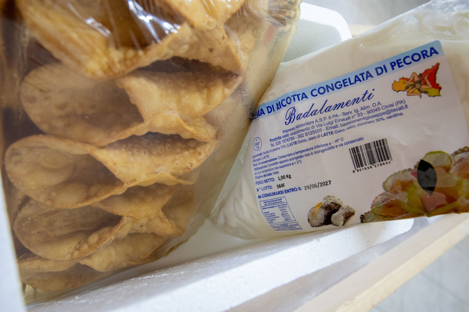 Coni di pasta sfoglia in un sacchetto e una confezione di ricotta congelata, entrambi all'interno di una borsa frigo bianca.