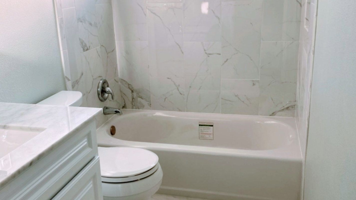 A bathroom with a toilet , sink , tub and shower.