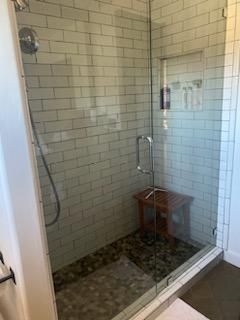 A bathroom with a walk in shower with a glass door.