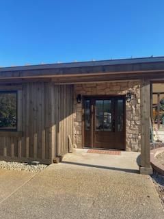 The front of a house with a wooden roof and a stone wall.