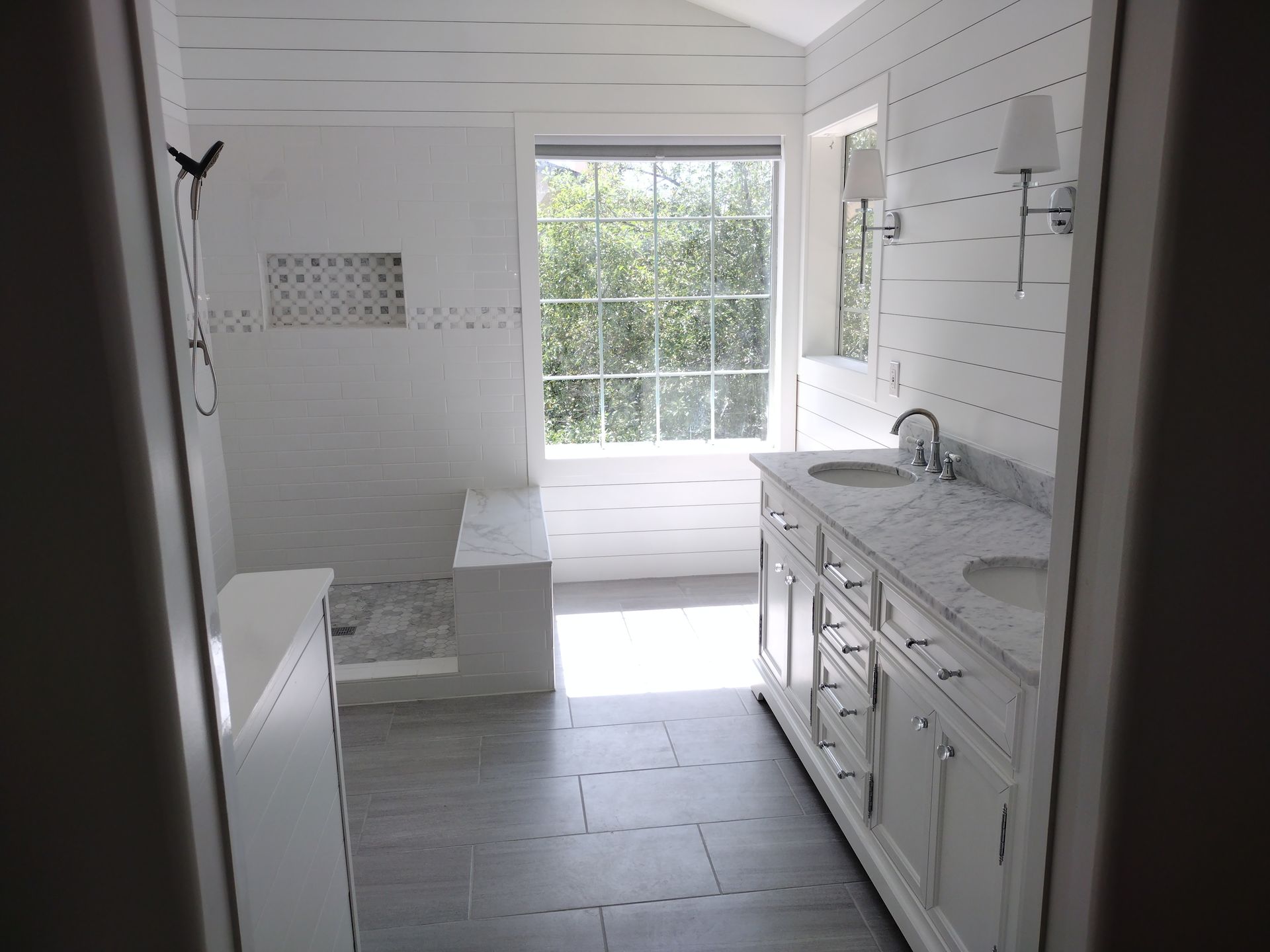 A bathroom with white cabinets , a sink and a window