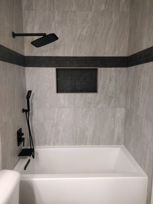 A bathroom with a bathtub and a shower head.