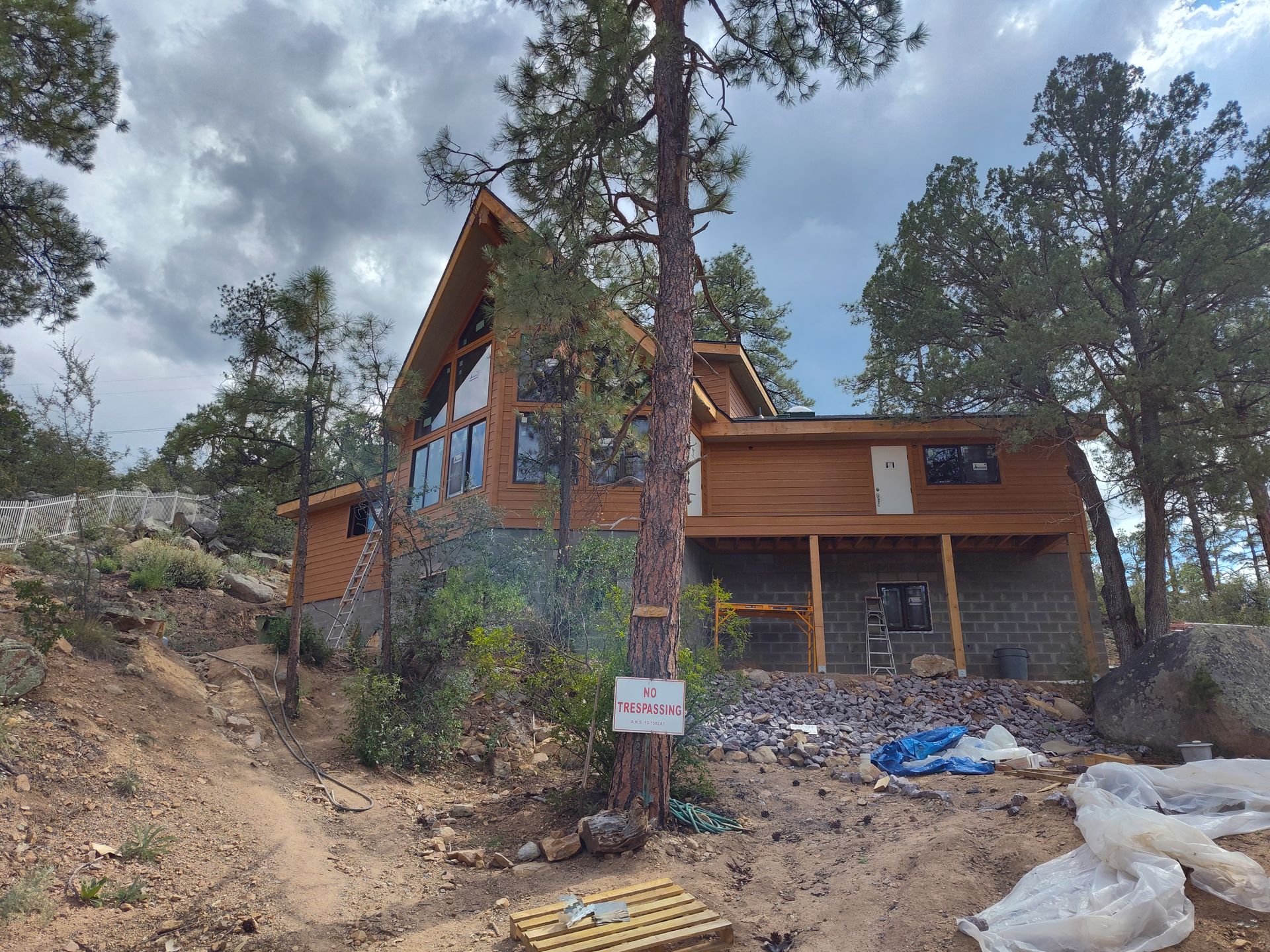 A large wooden house is sitting on top of a hill surrounded by trees.