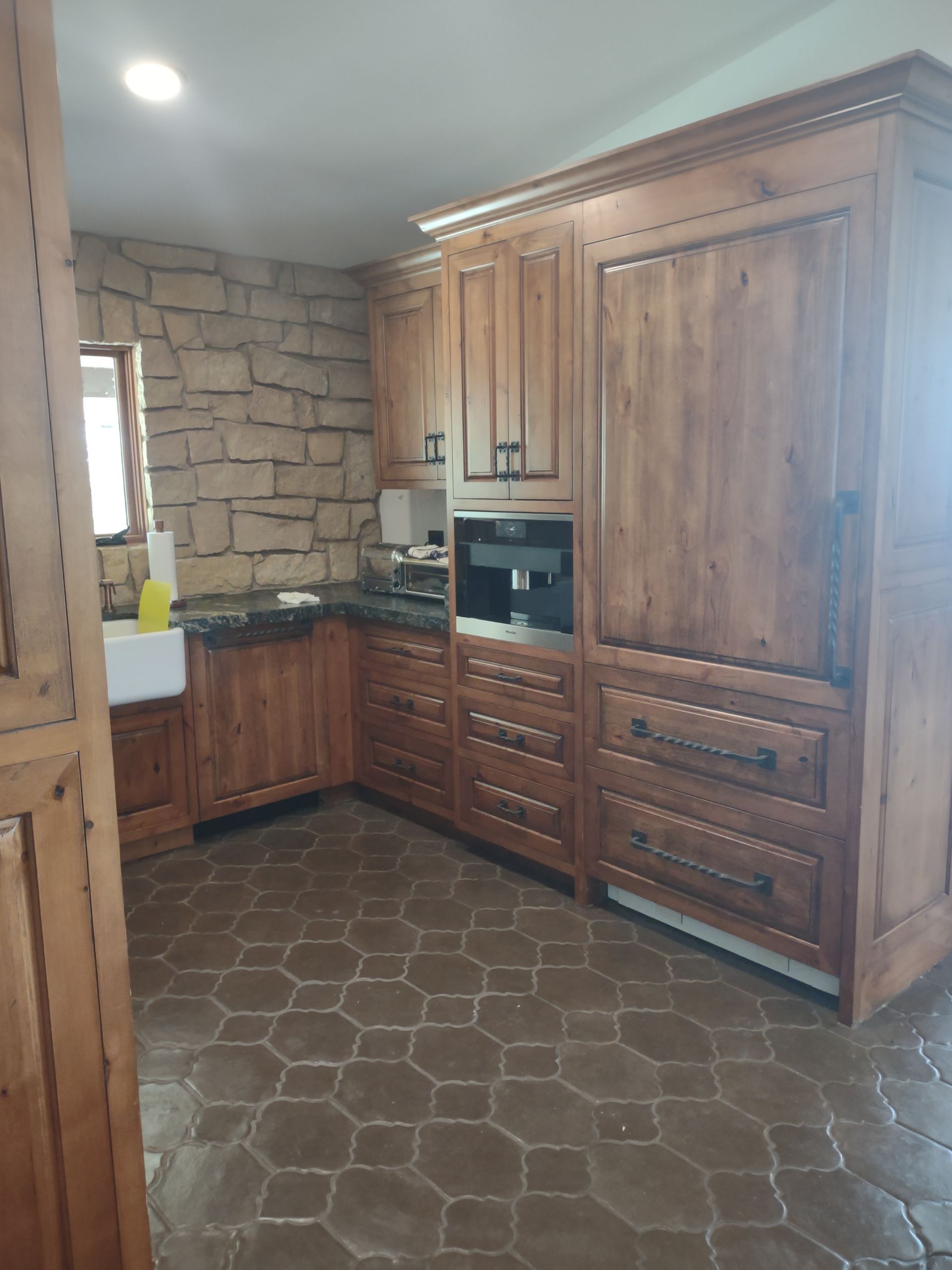 A kitchen with wooden cabinets and a tiled floor.