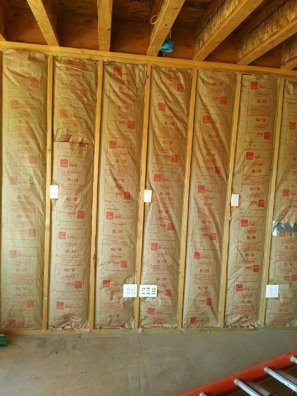 A wall with insulation on it and a ladder in the background.