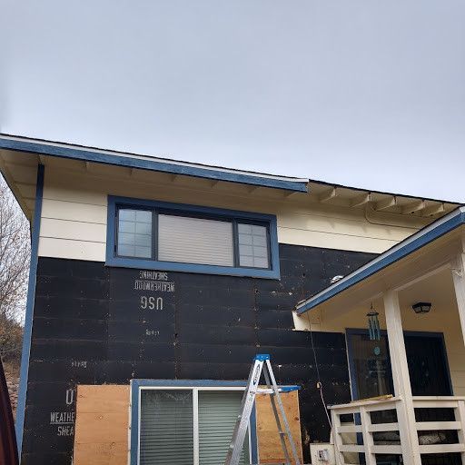 A house with a ladder in front of it is being remodeled.