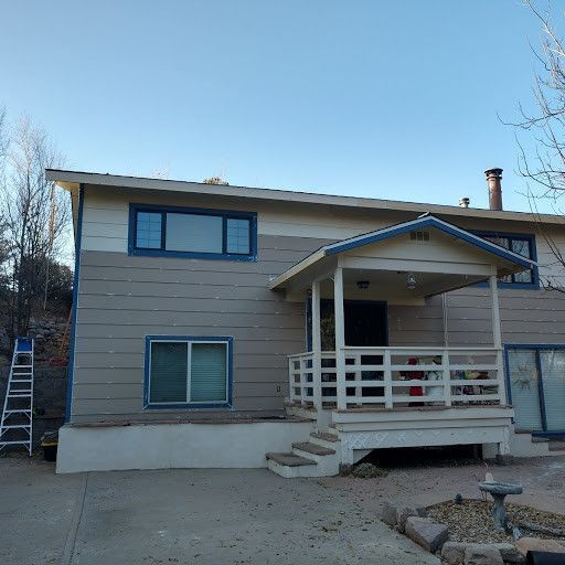 A house with a porch and a ladder in front of it.