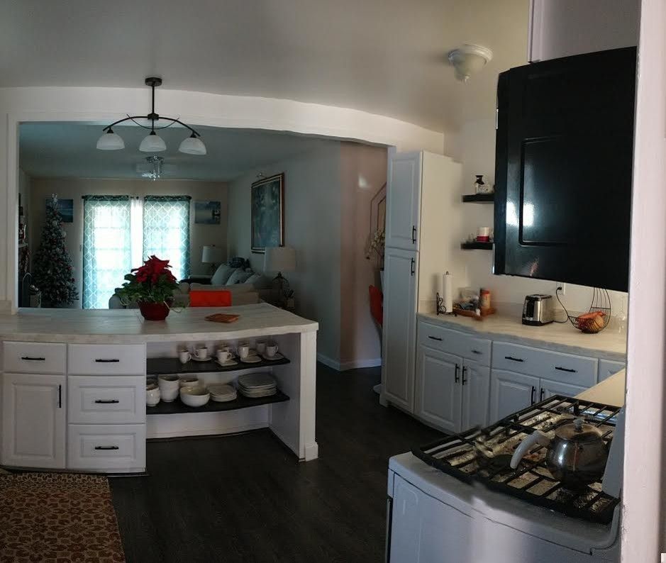 A kitchen with white cabinets and a stove top oven