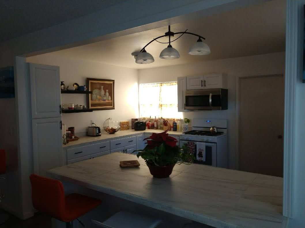 A kitchen with a table and chairs and a vase of flowers on it