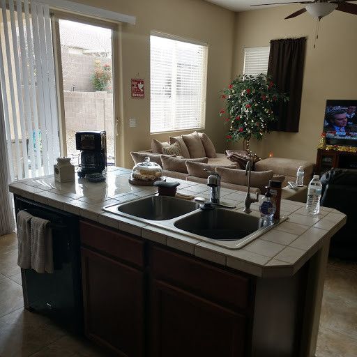 A kitchen with two sinks and a couch in the background.