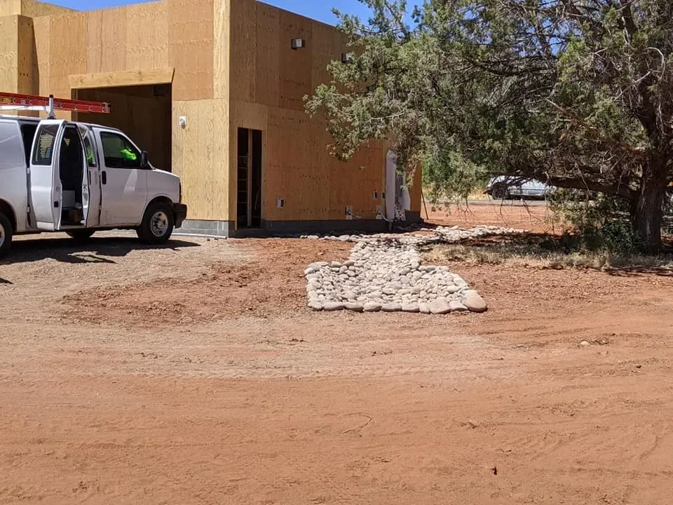 Construction site with a white van, building, and a pile of rocks.