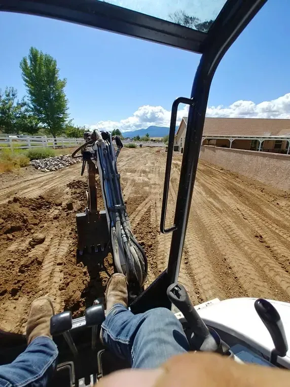 Operator inside excavator, digging earth on a sunny day.