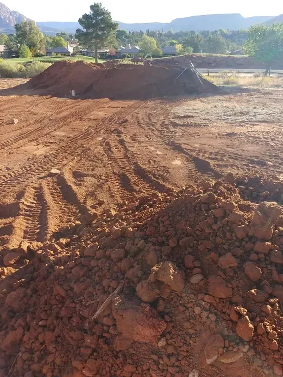 Dirt bike track under construction: red dirt, pile, tire tracks, outdoors.