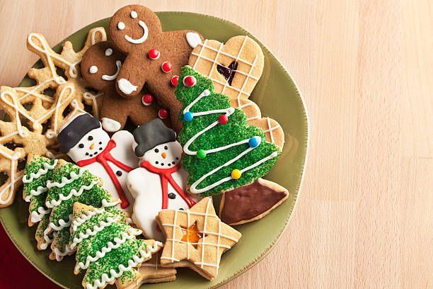 Christmas cookies on a green plate: gingerbread man, snowmen, trees, star, snowflake, hearts.