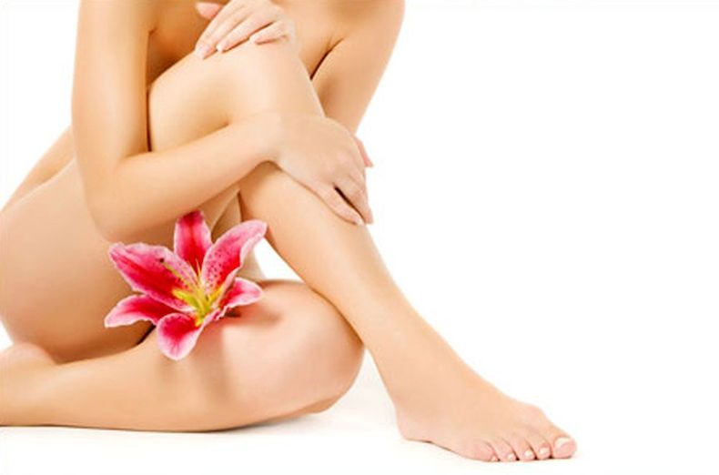 un'estetista mentre depila le gambe a una donna con una striscia di cera