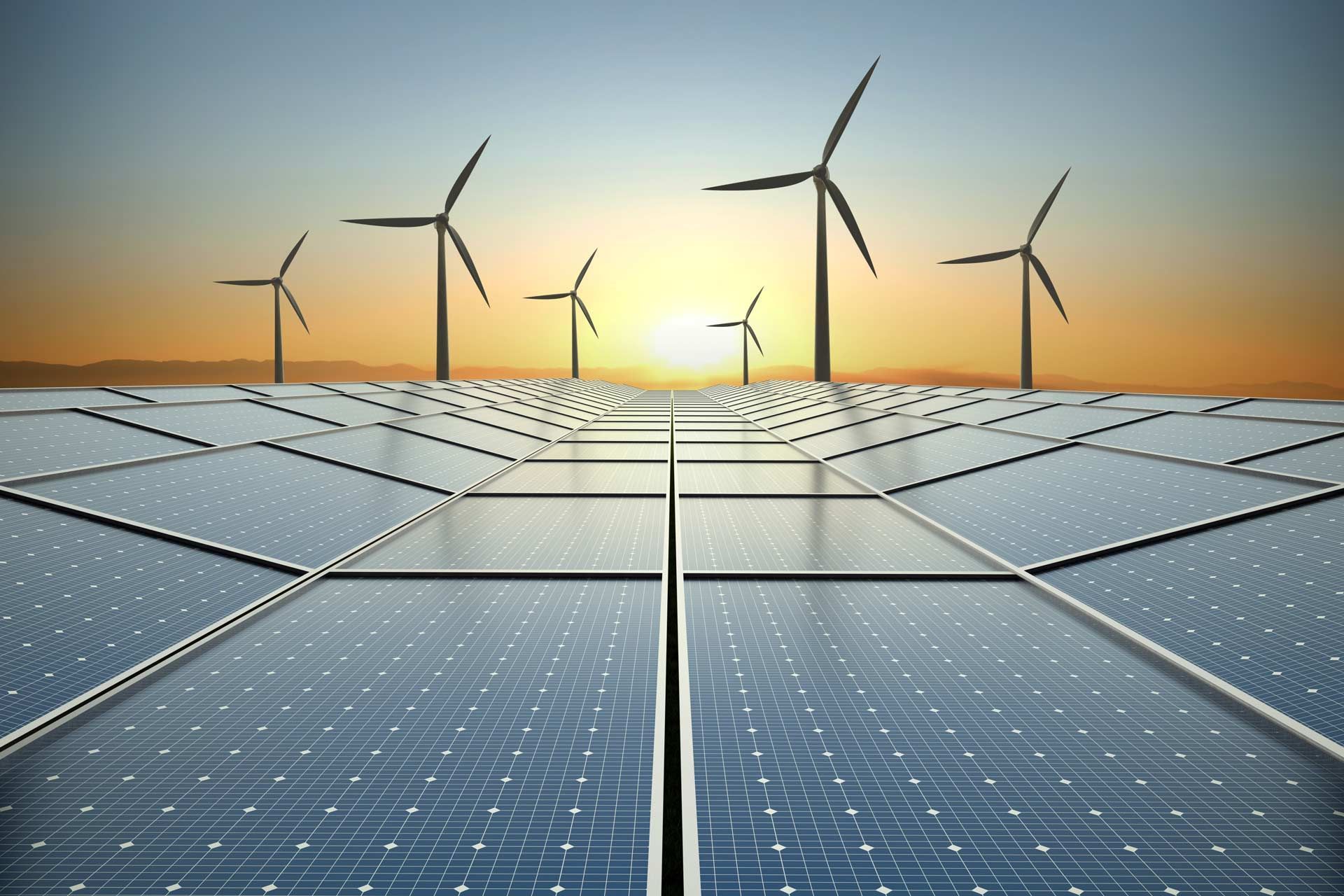 Solar panels in the foreground with wind turbines at sunset in the background, generating renewable energy.