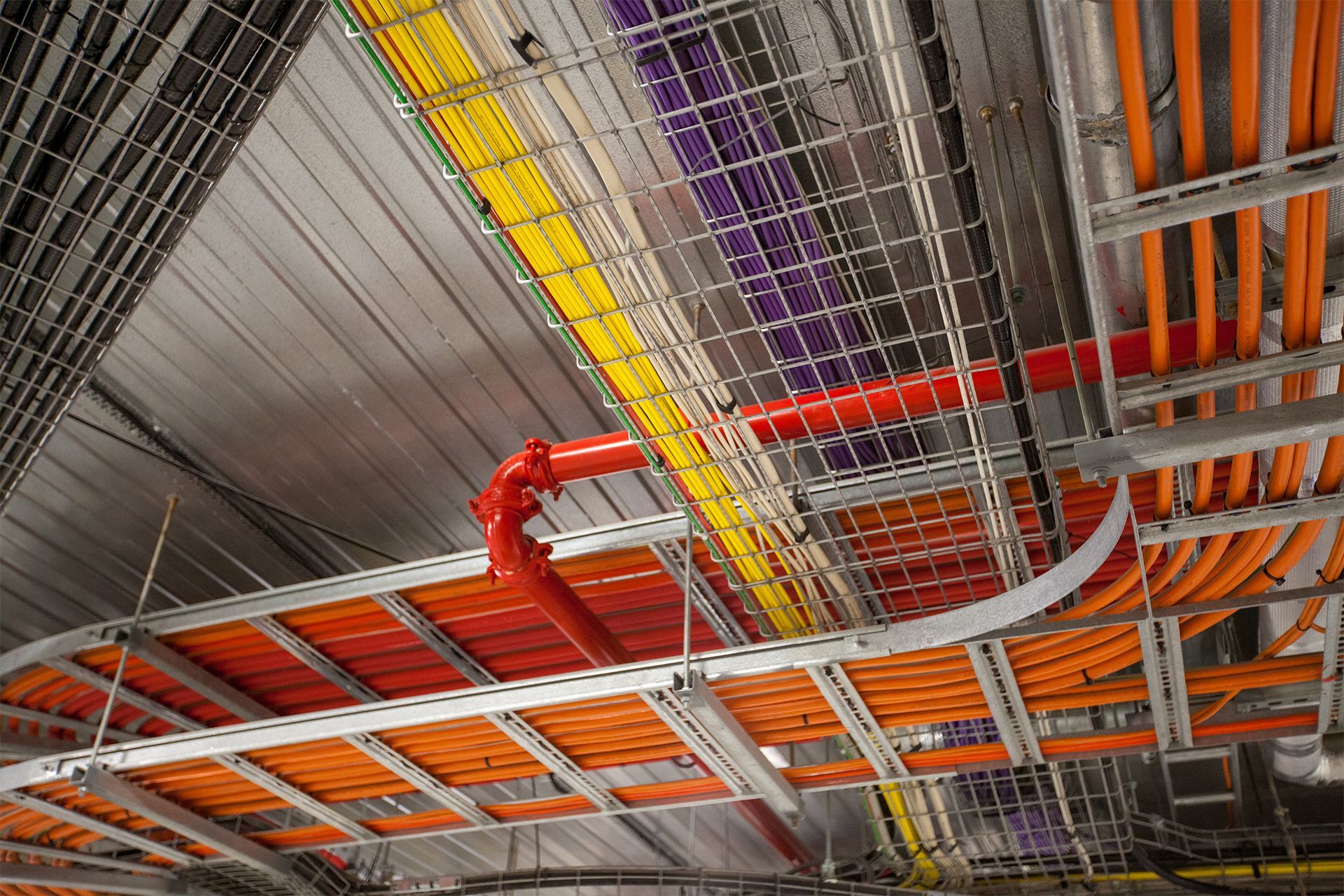 Overhead view of cable trays with various colored electrical wires and conduit.
