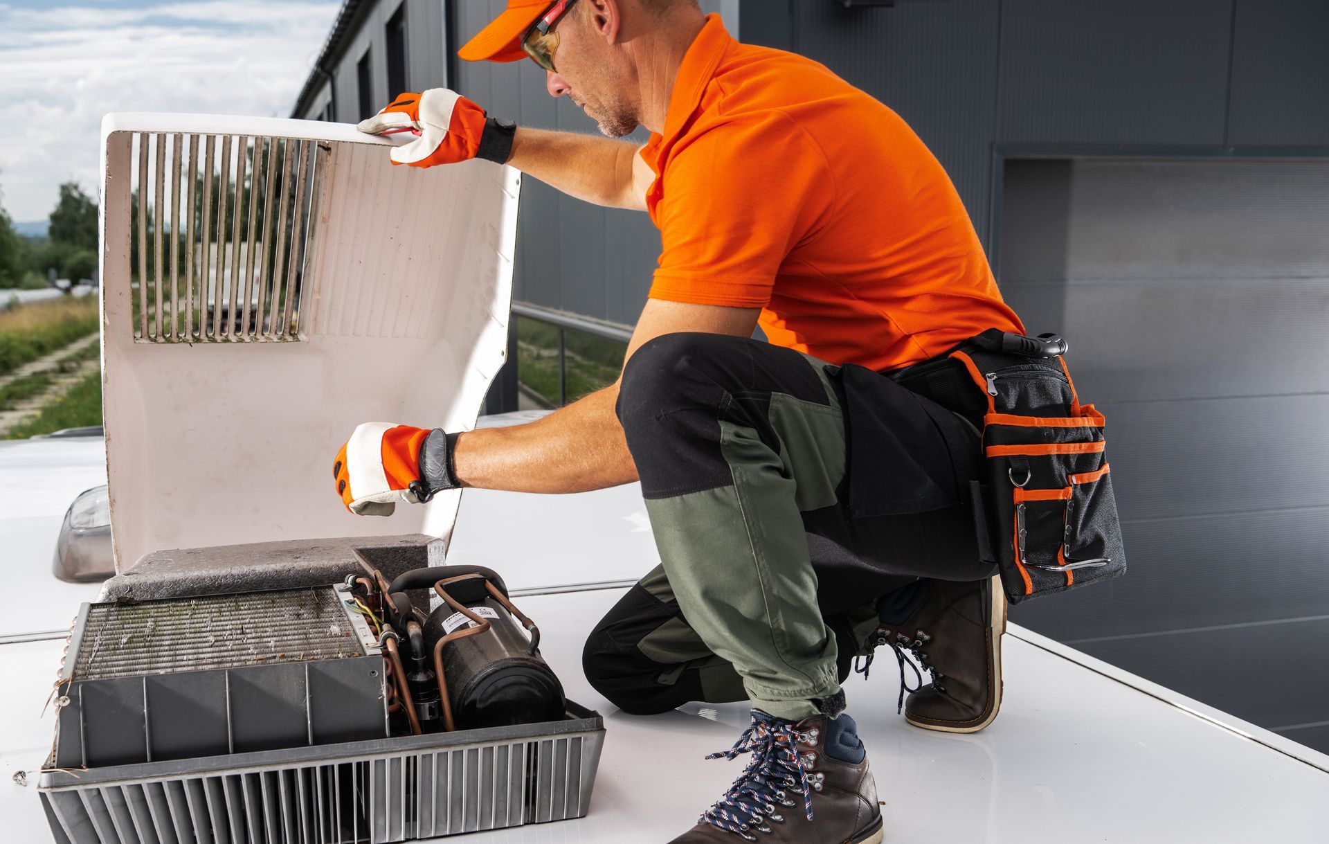 A man in an orange shirt is working on a roof.