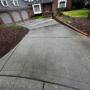 Driveway leading up to a brick house with garage, overcast day.