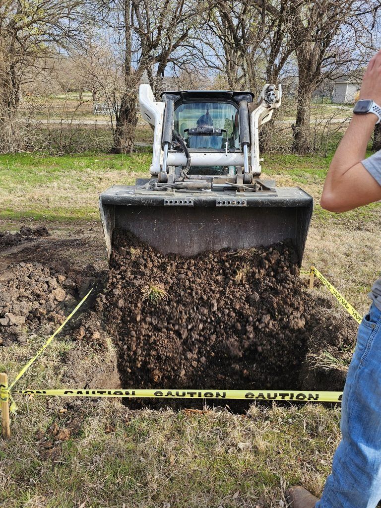 Bobcat skid-steer in a dirt pit, dumping soil. Yellow caution tape surrounds the hole.